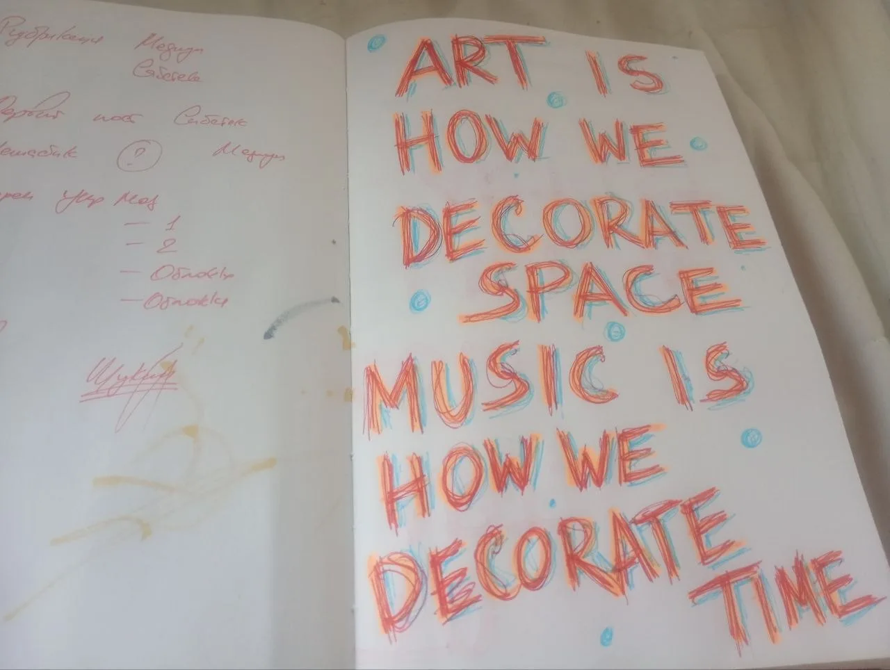 An original open sketchbook with handwritten words about art decorating space and music decorating time, coloured outlines and notes on the opposite page.