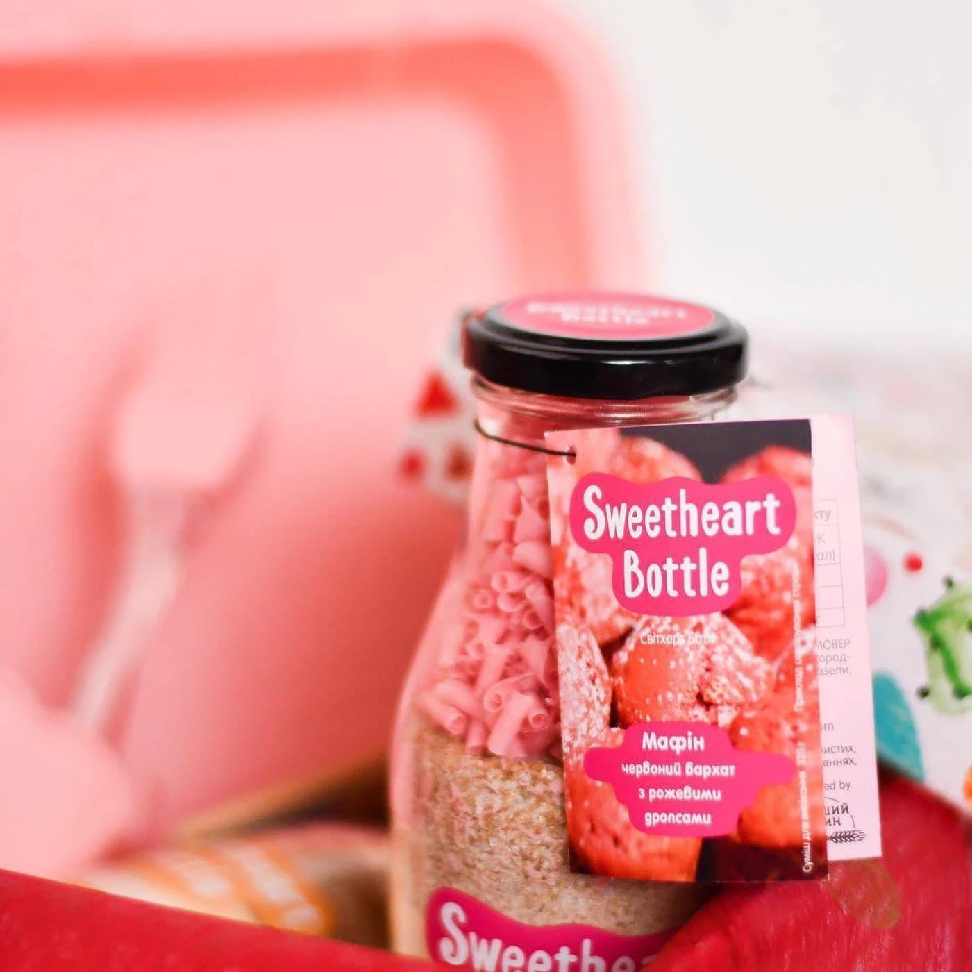 Sweetheart Bottle red velvet muffin mix in a glass bottle with a pink recipe booklet attached to its neck
