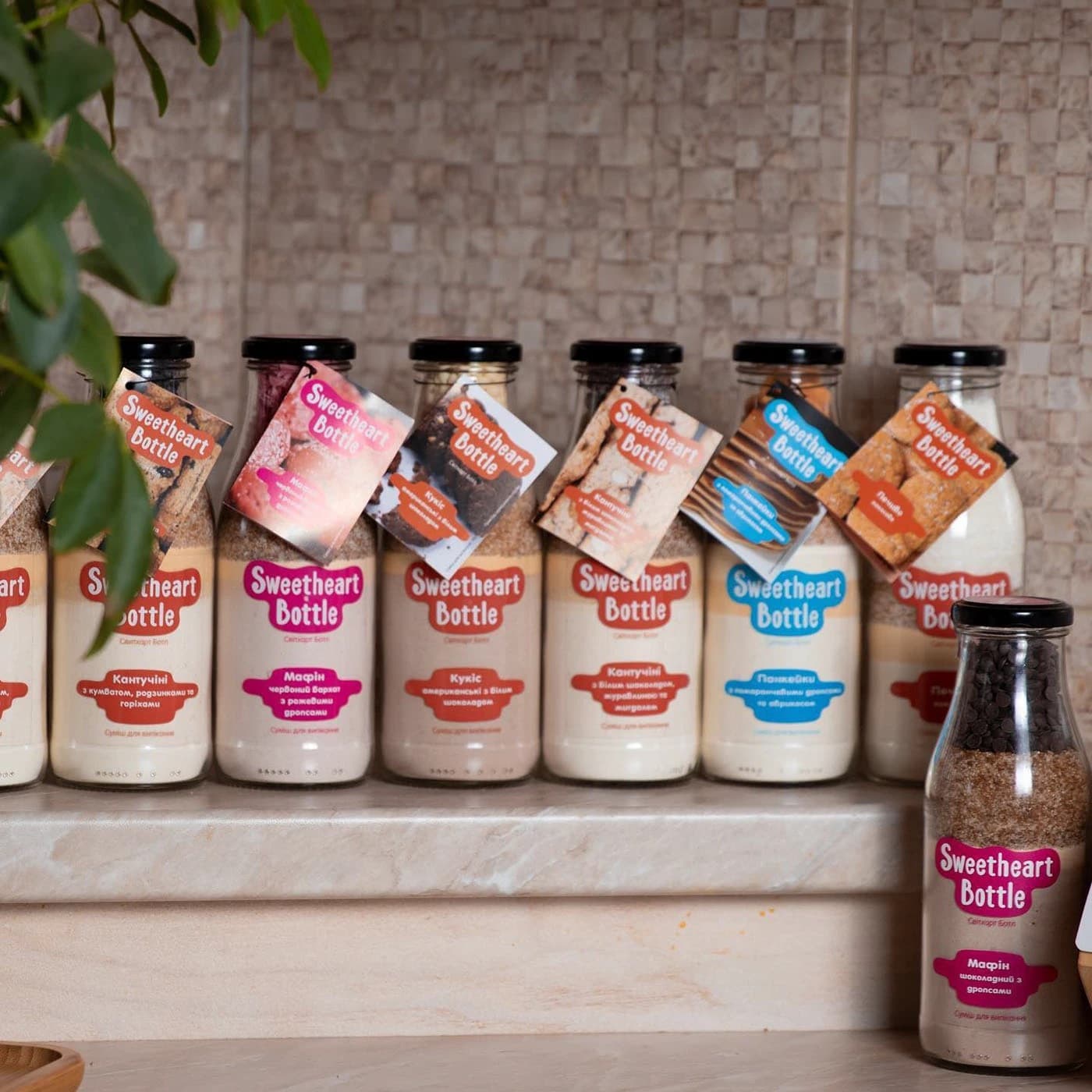Sweetheart Bottle baking mixes with layered ingredients and colour-coded labels displayed as a product range
