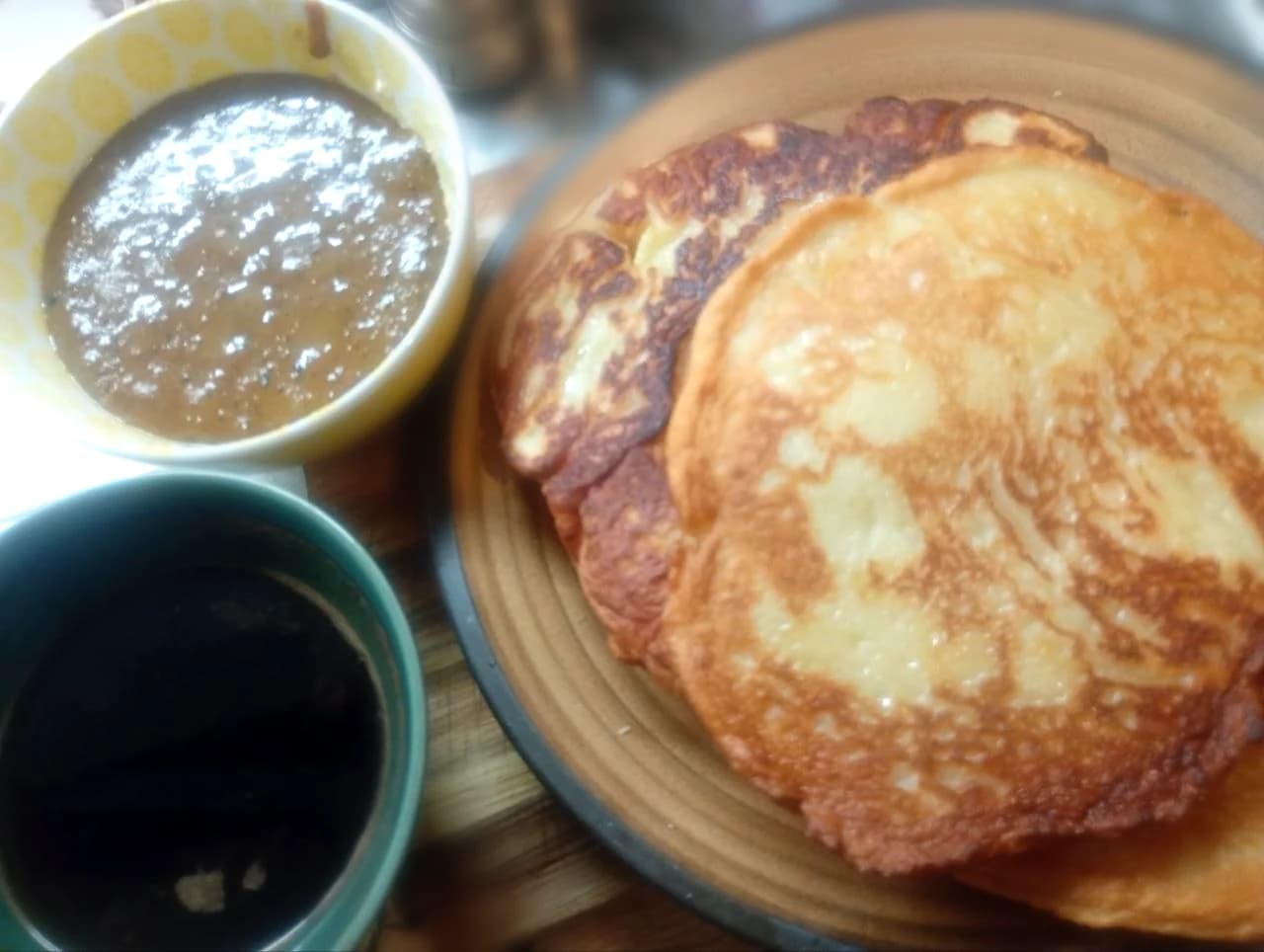 The author’s golden yogurt pancakes on a plate beside homemade brownish-green matcha condensed milk and a dark cup in a small kitchenette.