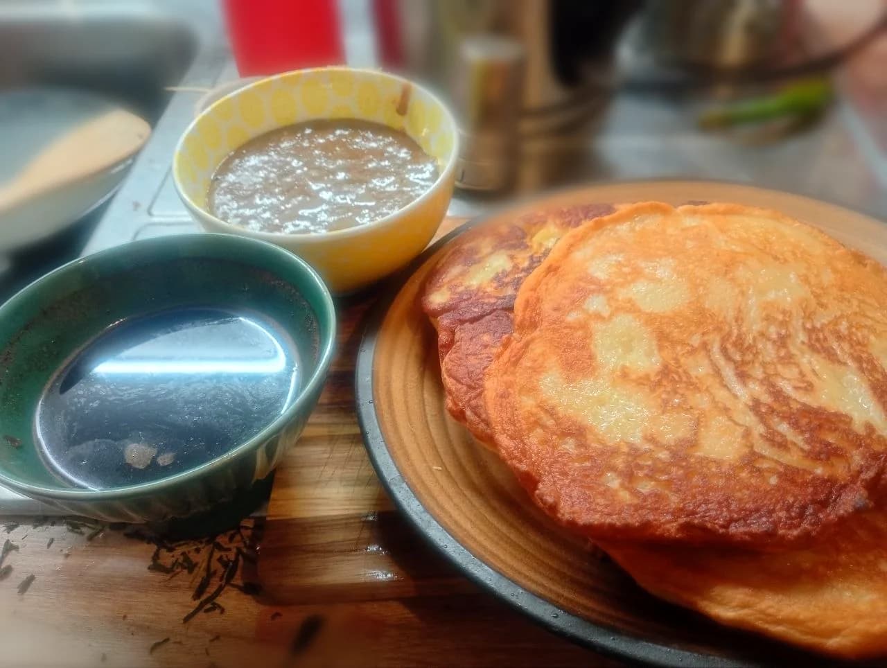 The author’s finished golden yogurt pancakes with homemade matcha condensed milk and a cup on the kitchenette counter.