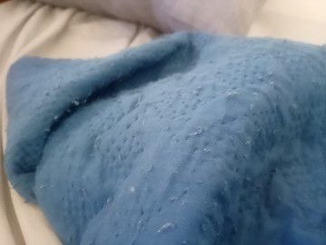 A close-up photograph of a textured blue blanket on pale bedding.